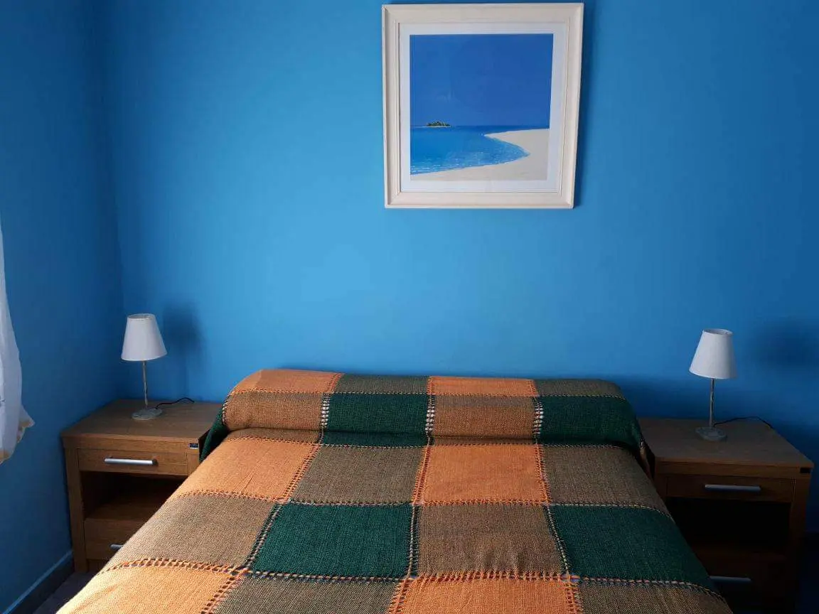 Dormitorio con paredes celestes y cama matrimonial