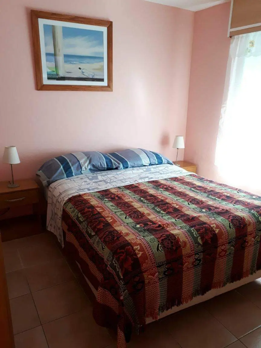Dormitorio con paredes rosa pastel y cama matrimonial